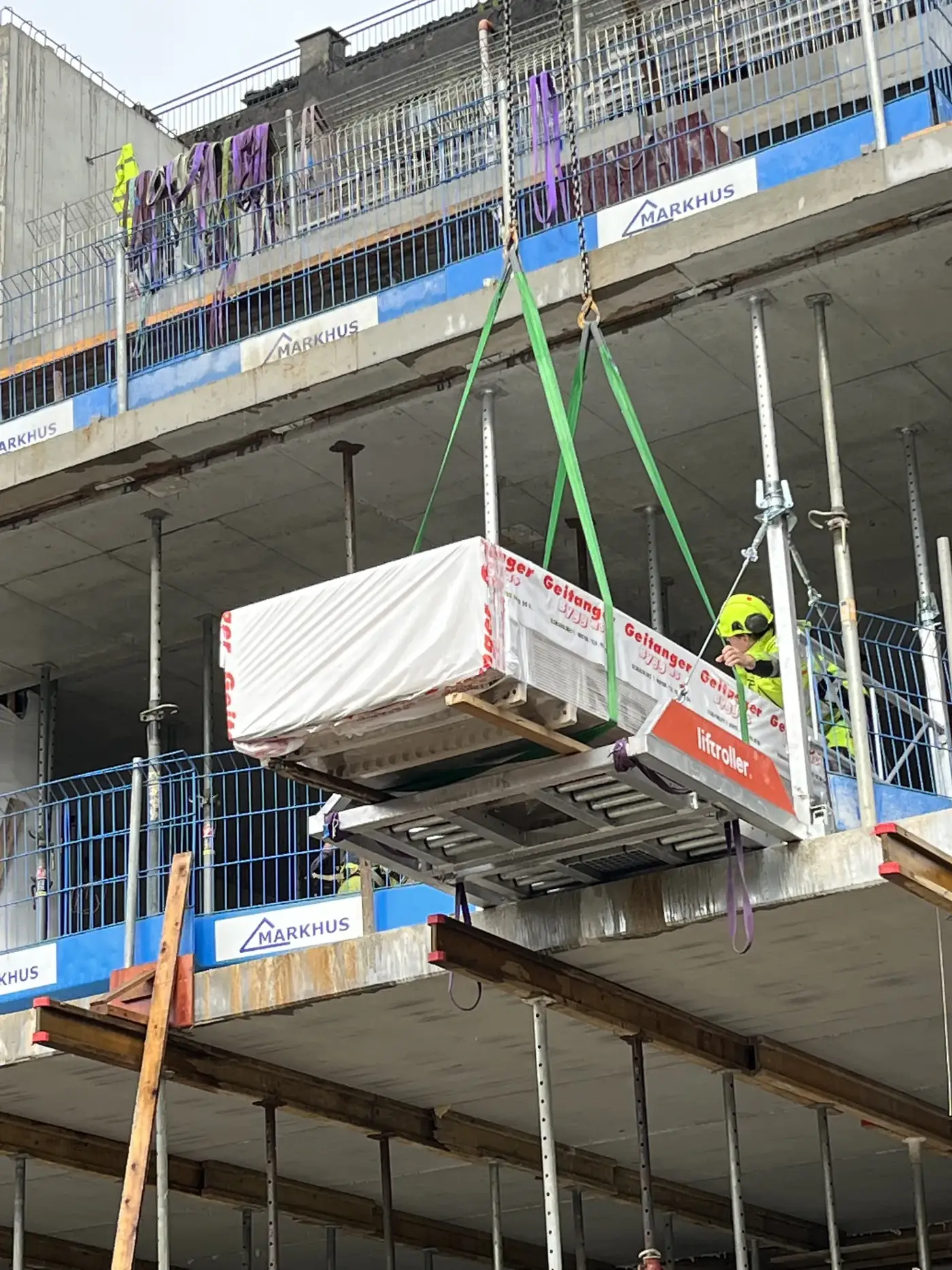 Liftroller Wall loading platform set into a window opening on an apartment building, with a pack of materials on the roller bed