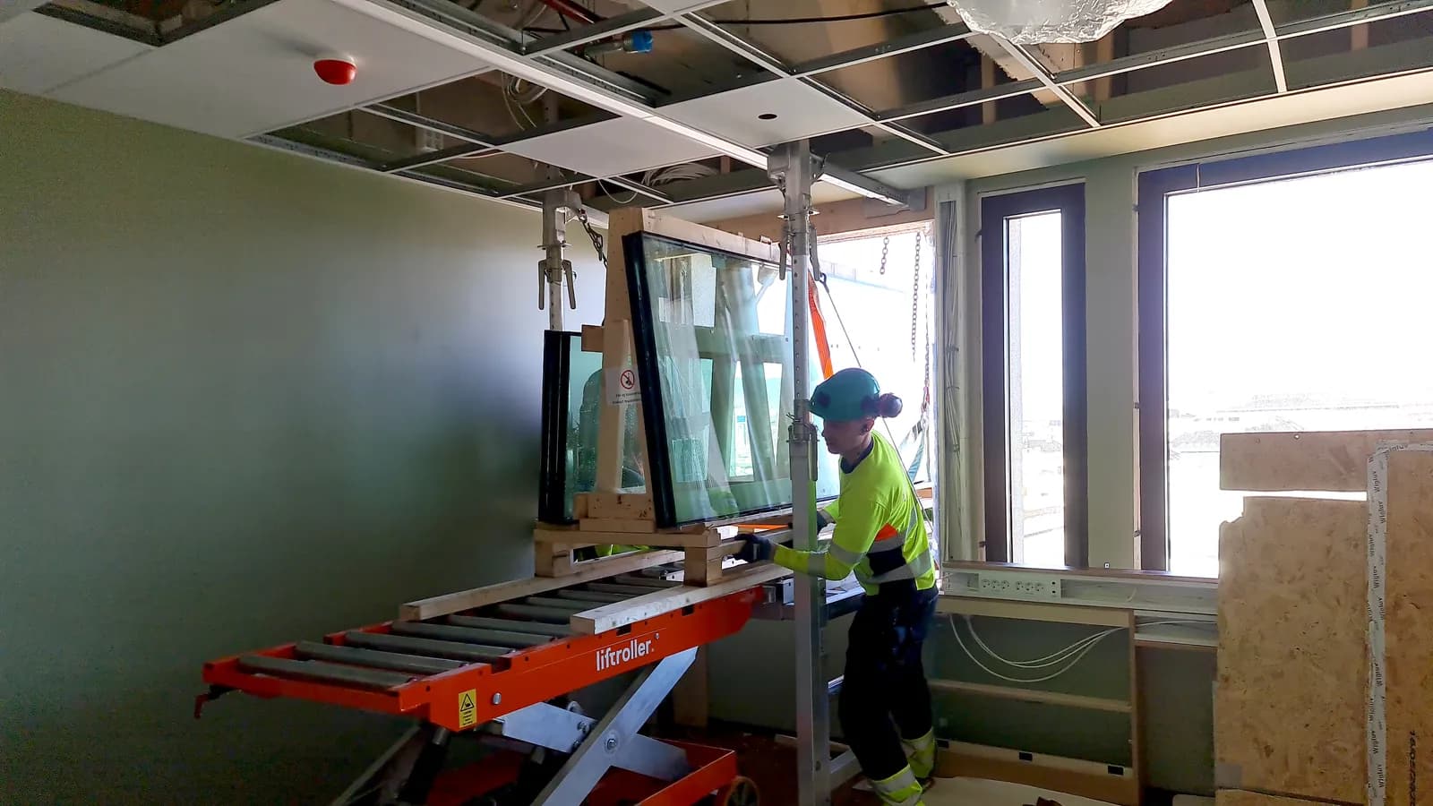 Crane lowering a pallet of building materials onto a Liftroller Wall platform projecting from an upper floor